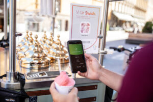 A person holding an ice cream and a smartphone