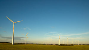 Wind power plants on field with blue sky