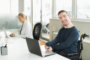 Man in wheel chair sitting by the computer