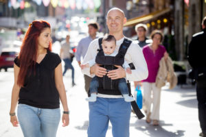 Family walking on the street with father carrying baby